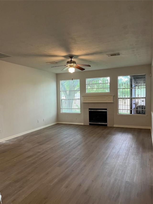 unfurnished living room featuring visible vents, ceiling fan, plenty of natural light, and dark wood finished floors