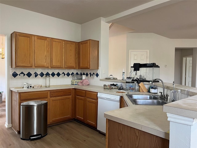 kitchen featuring dishwasher, light countertops, a sink, and wood finished floors