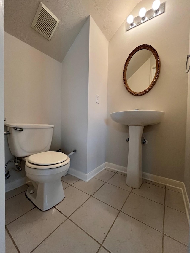 bathroom with visible vents, baseboards, toilet, vaulted ceiling, and tile patterned floors