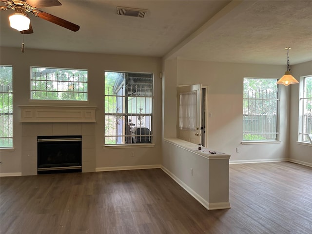 unfurnished living room with visible vents, baseboards, a tiled fireplace, ceiling fan, and wood finished floors