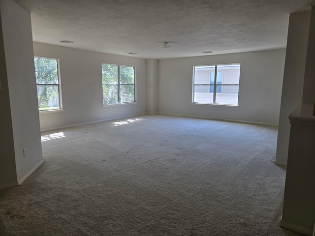 carpeted empty room featuring a textured ceiling and baseboards