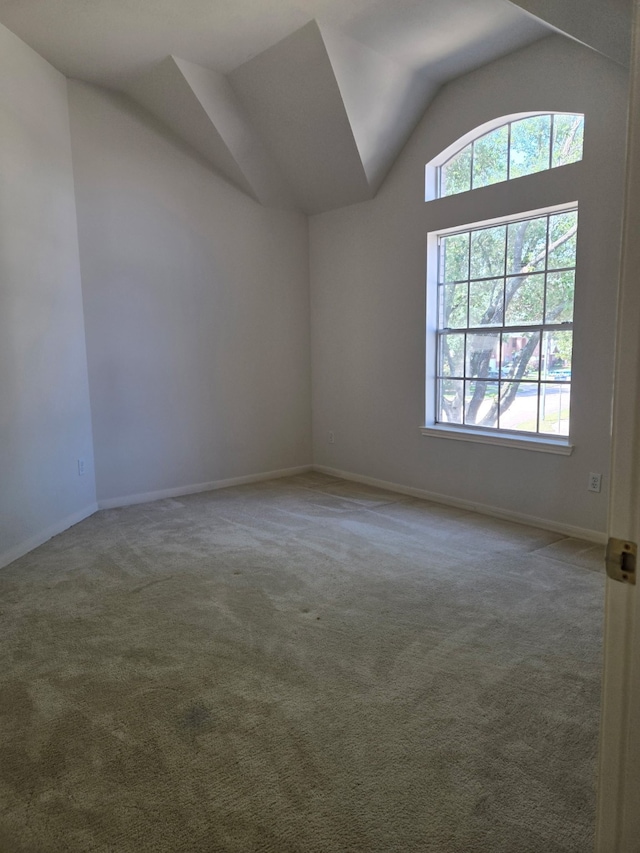 empty room with baseboards, lofted ceiling, and carpet floors