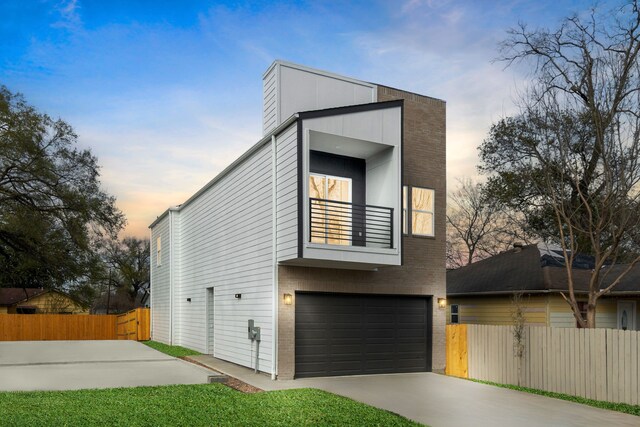 view of front of property with a balcony, fence, a garage, and concrete driveway
