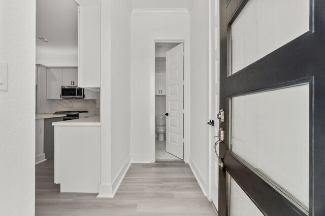 foyer featuring baseboards, visible vents, crown molding, and light wood-style flooring