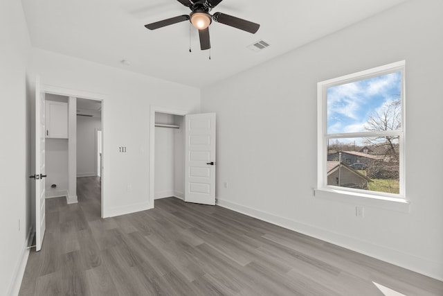 unfurnished bedroom featuring baseboards, visible vents, a closet, and wood finished floors