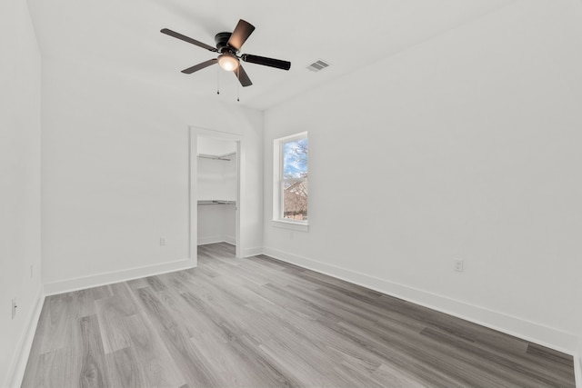 unfurnished bedroom with a closet, visible vents, baseboards, wood finished floors, and a ceiling fan