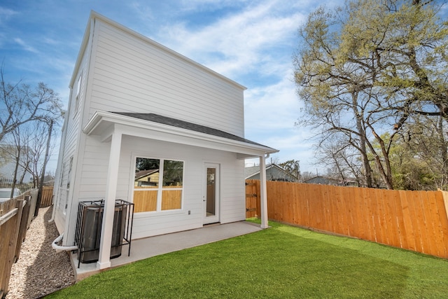 rear view of property with a fenced backyard and a lawn