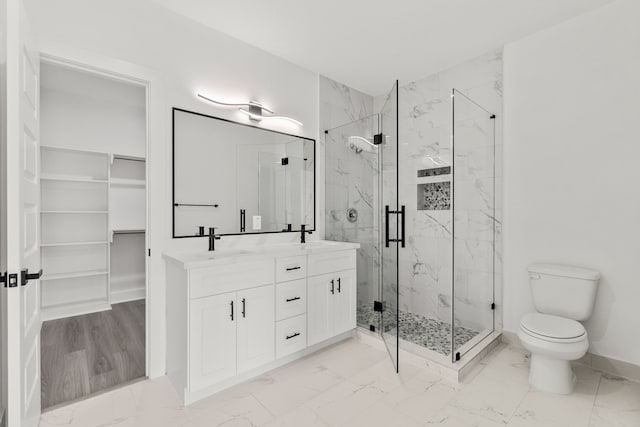bathroom with a marble finish shower, toilet, marble finish floor, a sink, and double vanity
