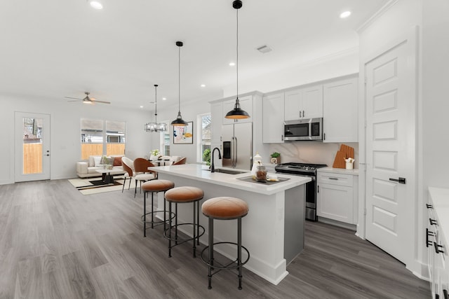 kitchen featuring a kitchen breakfast bar, stainless steel appliances, ceiling fan with notable chandelier, a sink, and visible vents