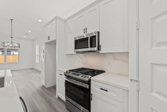 kitchen featuring white cabinetry, a notable chandelier, appliances with stainless steel finishes, and light wood finished floors