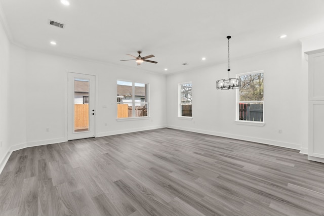 unfurnished living room featuring recessed lighting, ceiling fan with notable chandelier, baseboards, visible vents, and wood finished floors