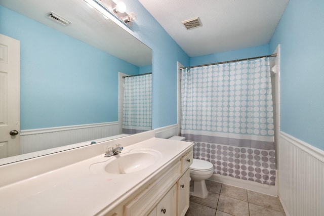 full bath with vanity, toilet, a wainscoted wall, and visible vents