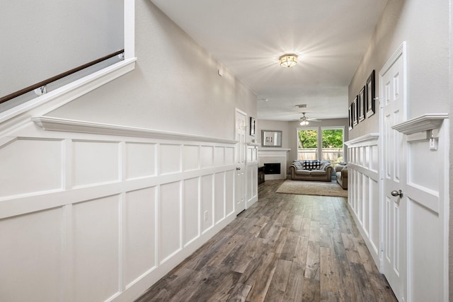 corridor with wainscoting, visible vents, dark wood-type flooring, and a decorative wall