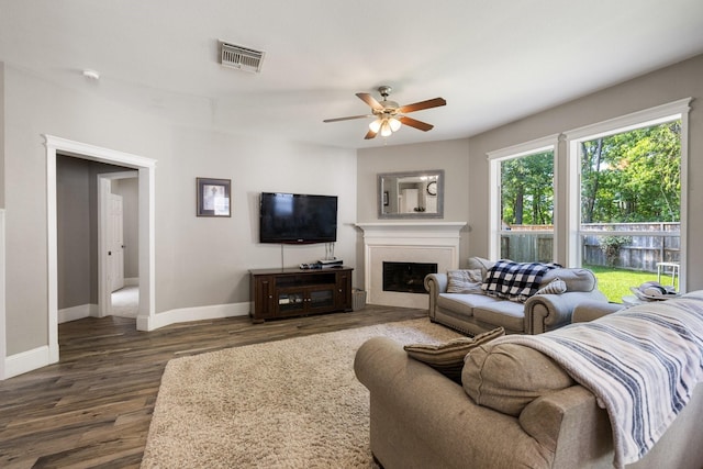 living room featuring ceiling fan, a fireplace, baseboards, dark wood-type flooring, and visible vents