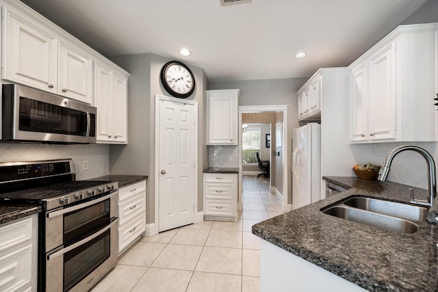 kitchen featuring a sink, decorative backsplash, light tile patterned flooring, baseboards, and appliances with stainless steel finishes