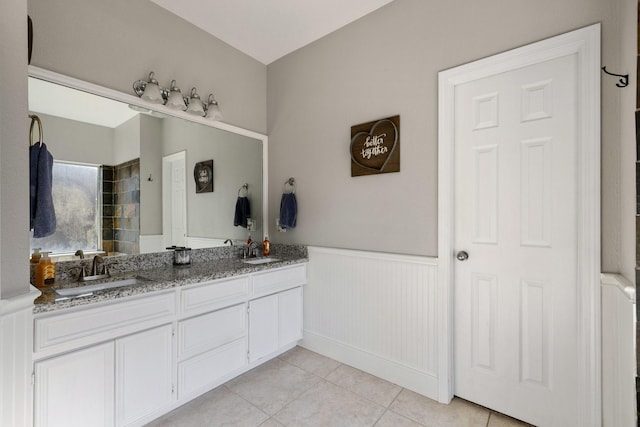 full bathroom featuring tile patterned flooring, a wainscoted wall, a sink, and double vanity