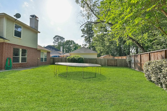 view of yard with a trampoline and a fenced backyard