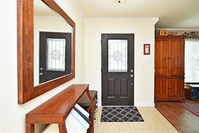 foyer entrance with baseboards, ornamental molding, and light tile patterned floors