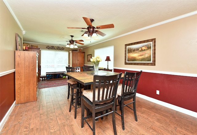 dining room with baseboards, wood finished floors, ceiling fan, and crown molding