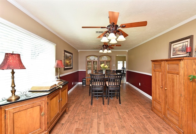 dining space featuring a ceiling fan, wood finished floors, baseboards, ornamental molding, and visible vents