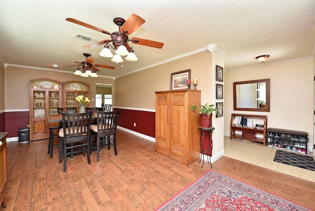 dining area featuring a textured ceiling, wood finished floors, visible vents, and a ceiling fan