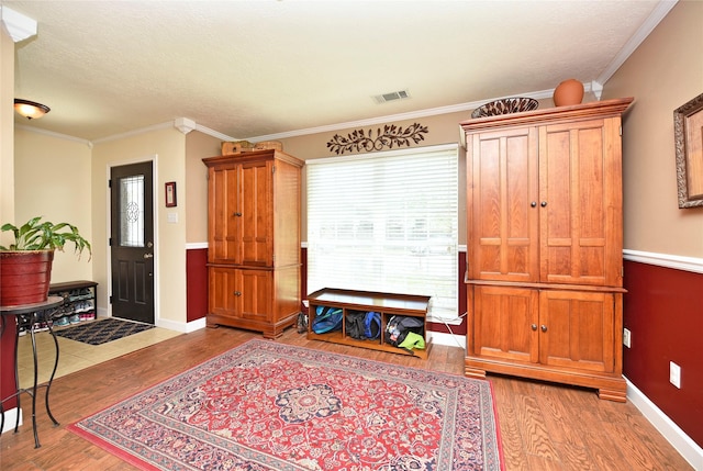 foyer with ornamental molding, wood finished floors, and visible vents