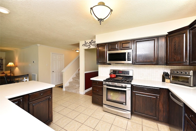 kitchen with decorative backsplash, dark brown cabinetry, stainless steel appliances, and light countertops