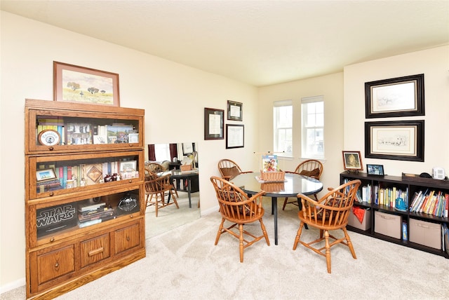 dining space featuring baseboards and light colored carpet