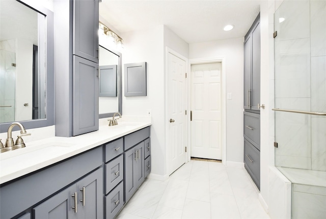 bathroom with double vanity, a shower stall, marble finish floor, and a sink
