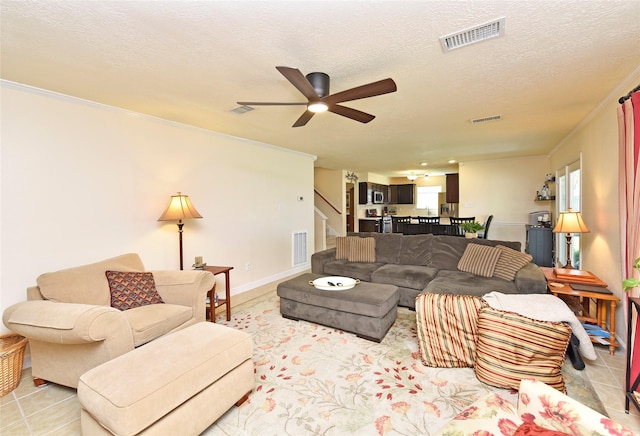 living area with visible vents, stairs, and ceiling fan