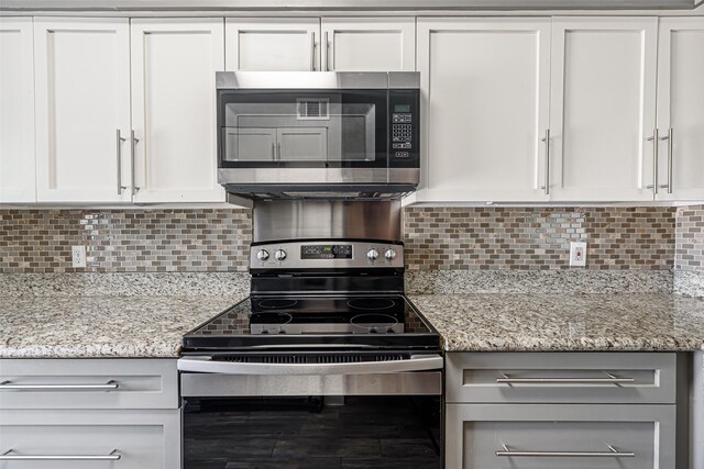 3226 Poe Dr, Montgomery, TX 77356 - kitchen featuring white cabinets, backsplash, light stone counters, and appliances with stainless steel finishes