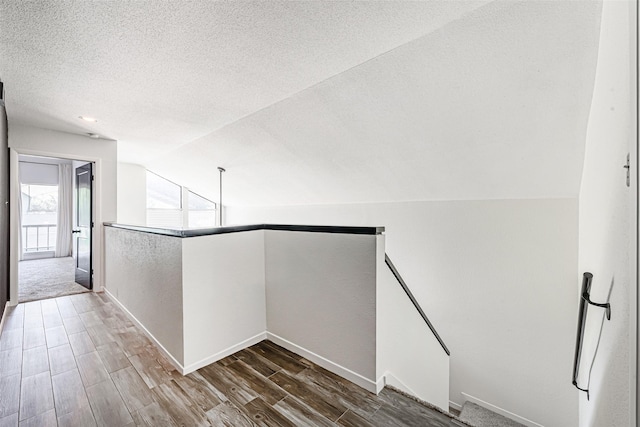 3226 Poe Dr, Montgomery, TX 77356 - corridor with baseboards, an upstairs landing, a textured ceiling, vaulted ceiling, and wood finished floors