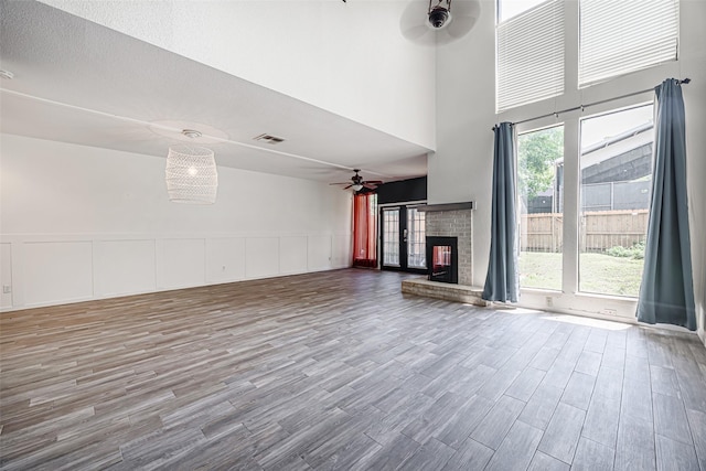 3226 Poe Dr, Montgomery, TX 77356 - unfurnished living room with visible vents, a high ceiling, a ceiling fan, a fireplace, and wood finished floors