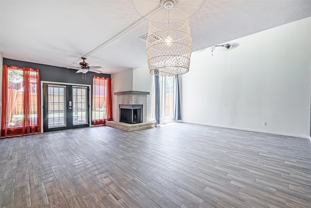 3226 Poe Dr, Montgomery, TX 77356 - unfurnished living room with wood finished floors, ceiling fan with notable chandelier, a brick fireplace, and a healthy amount of sunlight