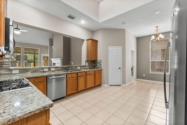 31 Trilling Bird Pl, The Woodlands, TX 77384 - kitchen with stainless steel appliances, tasteful backsplash, a ceiling fan, brown cabinets, and light tile patterned floors