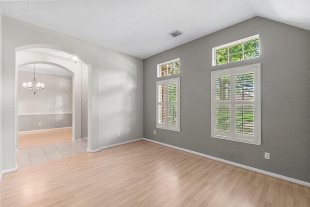 31 Trilling Bird Pl, The Woodlands, TX 77384 - empty room with wood finished floors, arched walkways, a chandelier, and vaulted ceiling