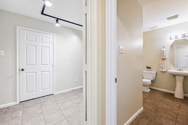7107 Grant Dr, Magnolia, TX 77354 - bathroom with toilet, tile patterned floors, baseboards, rail lighting, and a sink