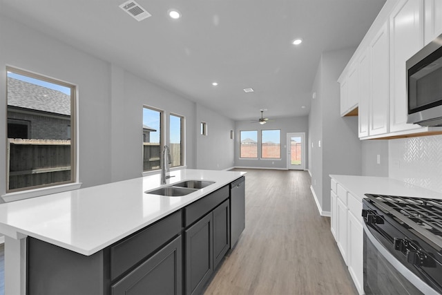 5028 Marcasca Dr, Katy, TX 77493 - kitchen with light wood-style flooring, white cabinetry, visible vents, appliances with stainless steel finishes, and a sink