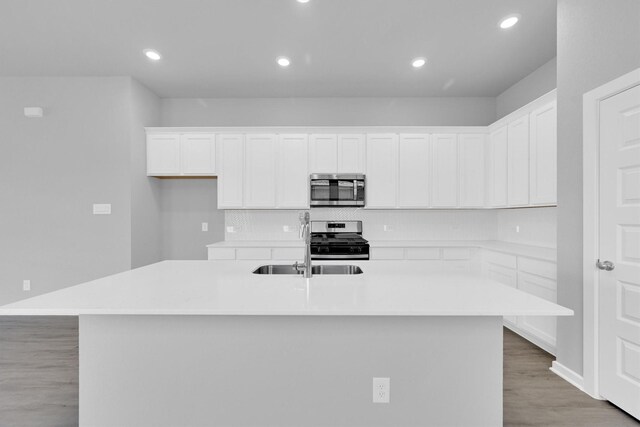 5028 Marcasca Dr, Katy, TX 77493 - kitchen featuring tasteful backsplash, light wood-type flooring, white cabinetry, stainless steel appliances, and a center island with sink