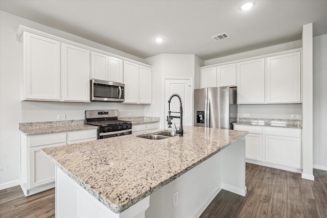 12260 Lady Eli Dr, Willis, TX 77318 - kitchen with stainless steel appliances, a center island with sink, dark wood finished floors, white cabinetry, and recessed lighting