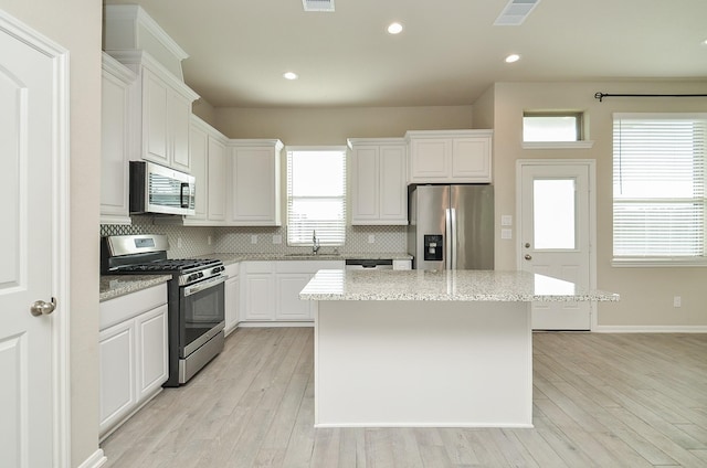 5203 Prairie Terrace Ln, Fulshear, TX 77441 - kitchen featuring a sink, a kitchen island, stainless steel appliances, light wood-style floors, and decorative backsplash