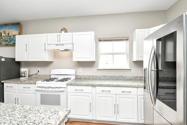 11314 Carla St, Houston, TX 77076 - kitchen with under cabinet range hood, white cabinetry, stainless steel fridge with ice dispenser, white gas range oven, and freestanding refrigerator