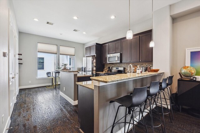 2718 Leeland St Unit A, Houston, TX 77003 - kitchen with stainless steel appliances, a peninsula, dark brown cabinetry, a center island, and backsplash