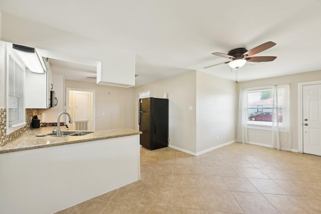 kitchen with light tile patterned flooring, a ceiling fan, freestanding refrigerator, a peninsula, and stainless steel microwave