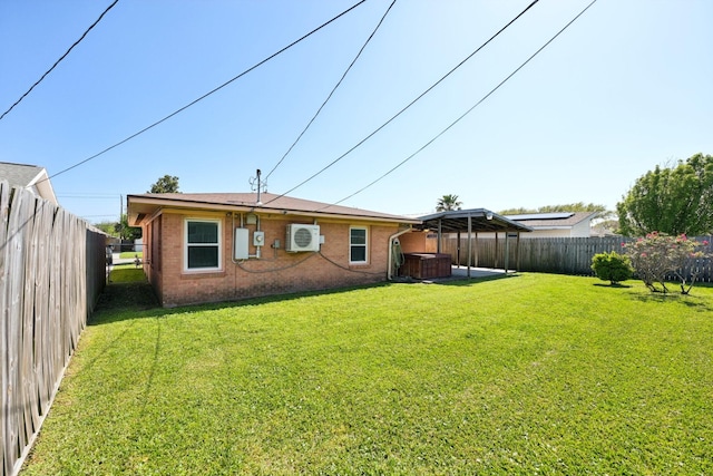 back of house with a hot tub, brick siding, a fenced backyard, and a yard
