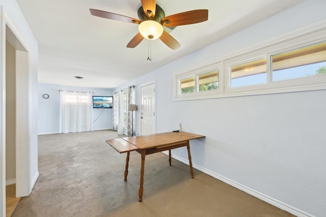 carpeted office space featuring a ceiling fan and baseboards