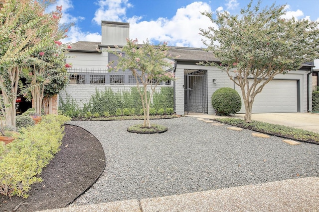 view of front of house featuring fence, driveway, brick siding, and a garage