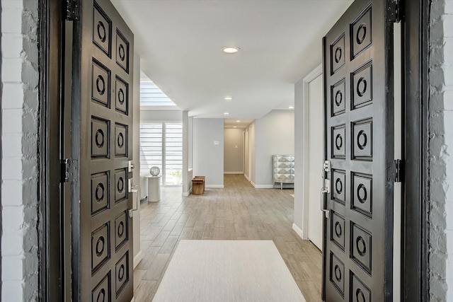 hallway featuring recessed lighting, light wood-style floors, and baseboards