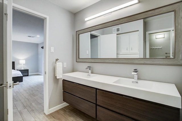 full bath with wood finished floors, visible vents, baseboards, and a sink