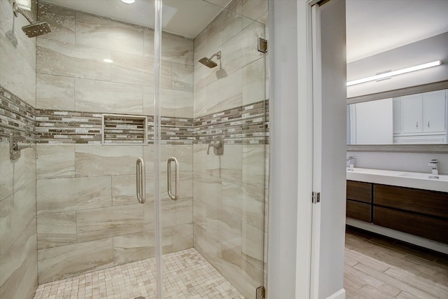 bathroom featuring vanity, wood finished floors, and a stall shower